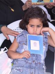 A prisoner’s daughter carrying the picture of her father