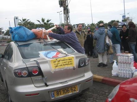 Gadi Kenny fastens personal gifts to the top of his car, Adam Keller briefs journalists