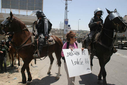 A Ta'ayush protester between the horses 