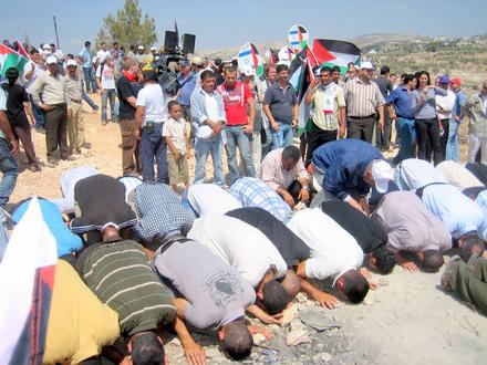 Muslim demonstrators pray in front of the fence